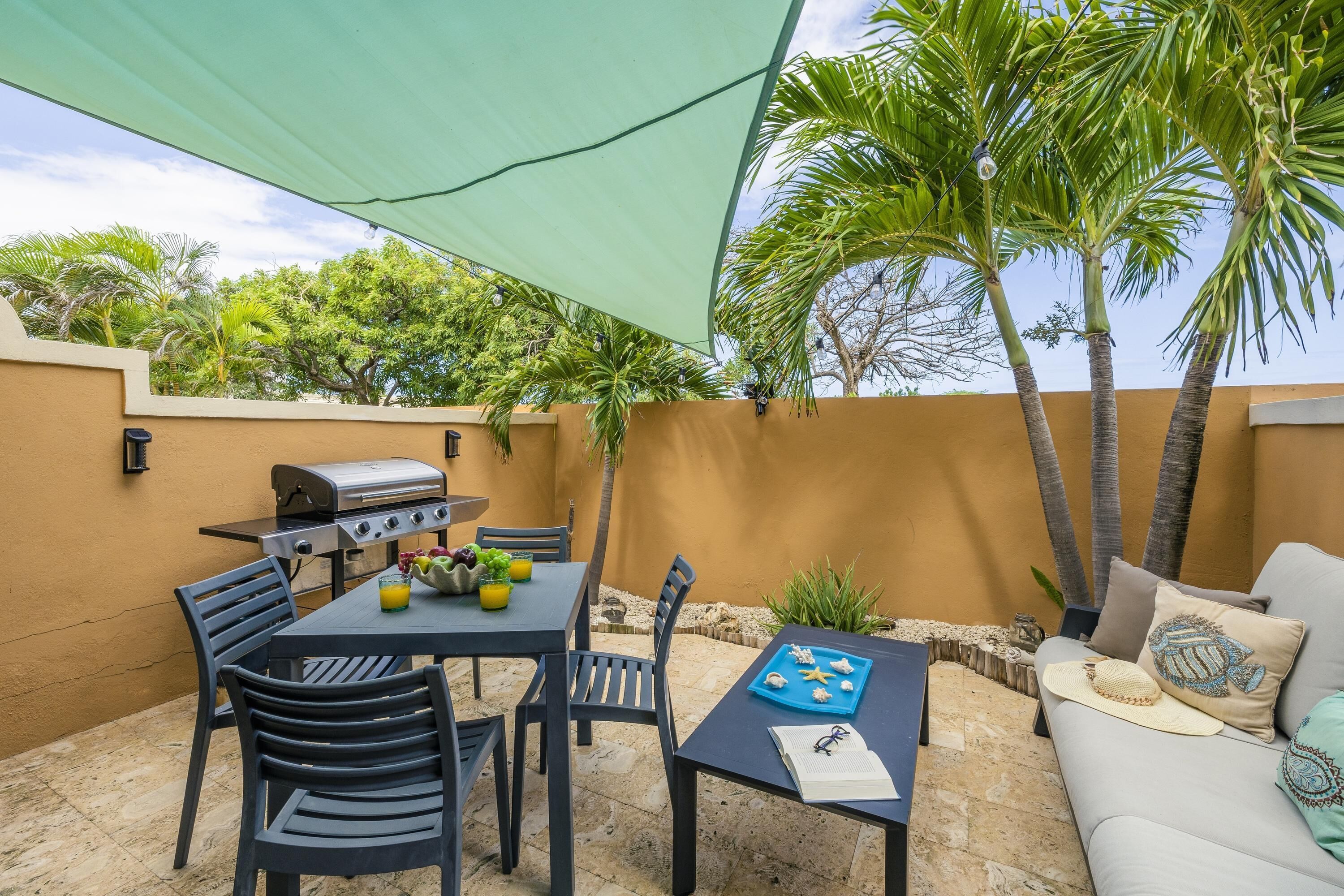Une terrasse extérieure avec une table, des chaises, un barbecue et un canapé.