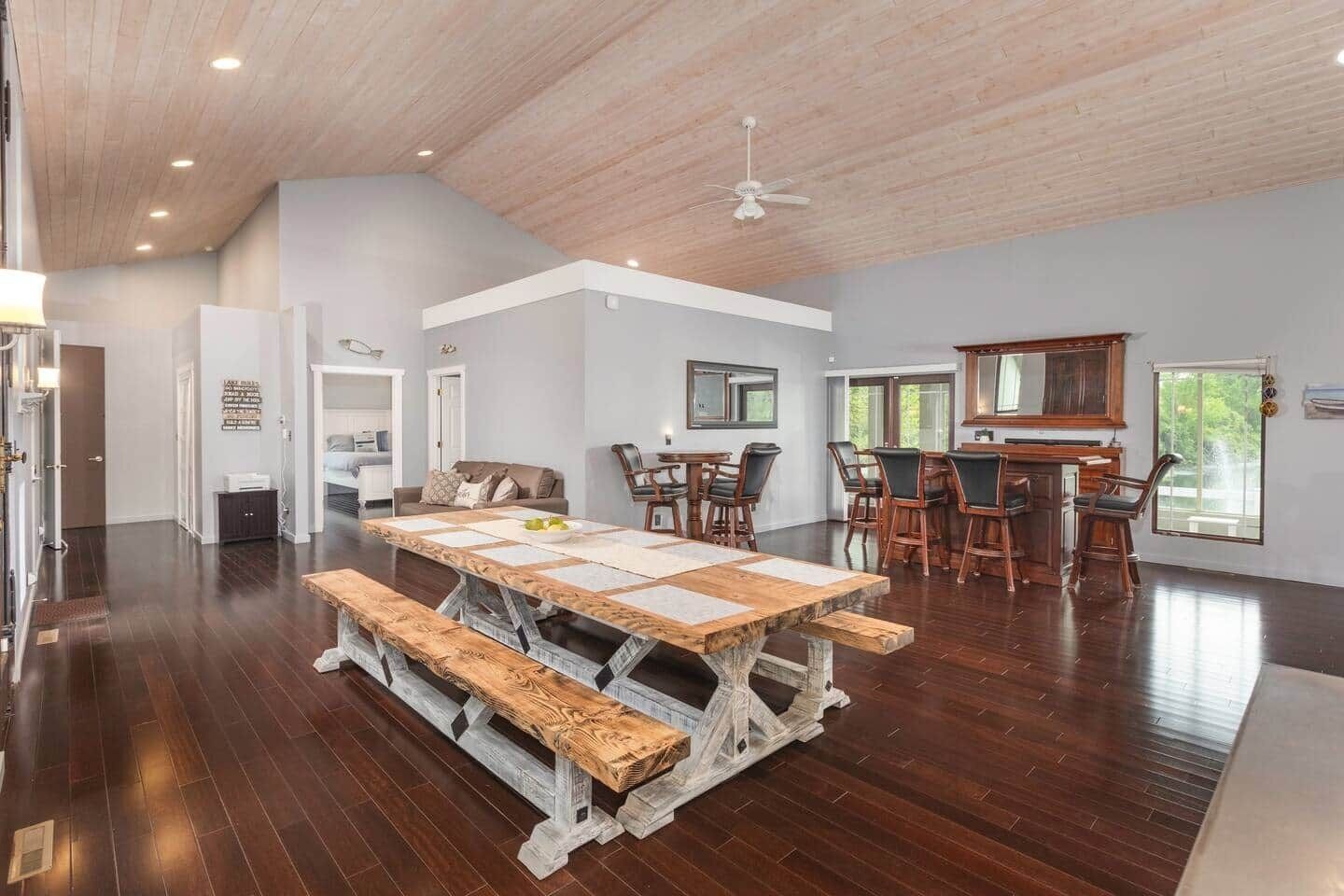 Un'ampia sala da pranzo con un grande tavolo di legno e panche, circondata da sedie.