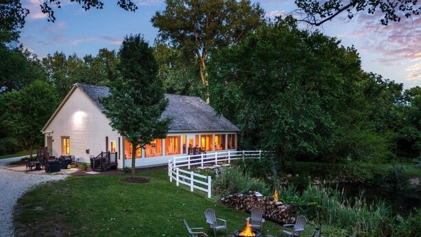 Une maison dotée d’un porche abrité, d’un foyer extérieur et de meubles de jardin.