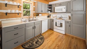 A kitchen with grey cabinets, a white microwave, and a wooden floor. - Boone/Blowing Rock Cabin: Hot Tub, Mountain Views, Sleeps 8, Peaceful, Private (Vilas)