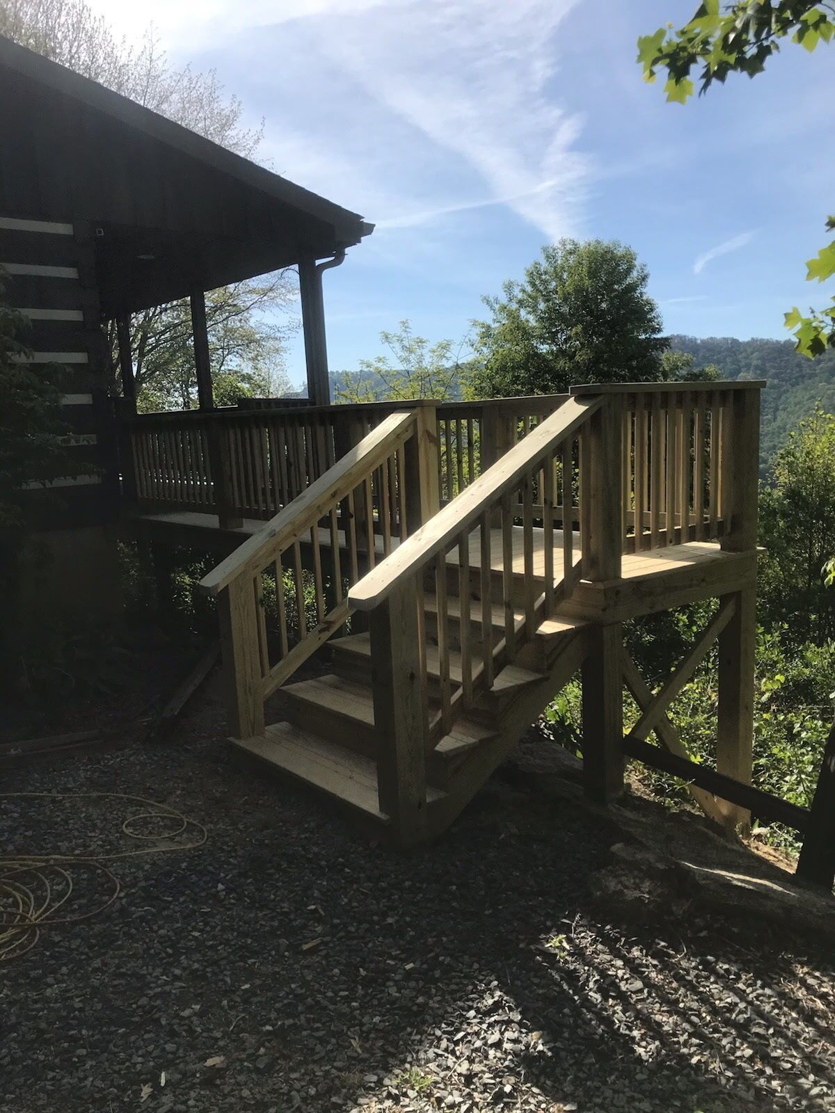 A wooden staircase leading to a deck with a view of a forested area.