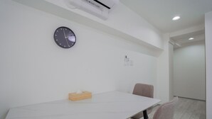 A modern conference room with a white table, two chairs, a clock, and an air conditioning unit on the wall. - STAY OSAKA NANBA (Osaka)