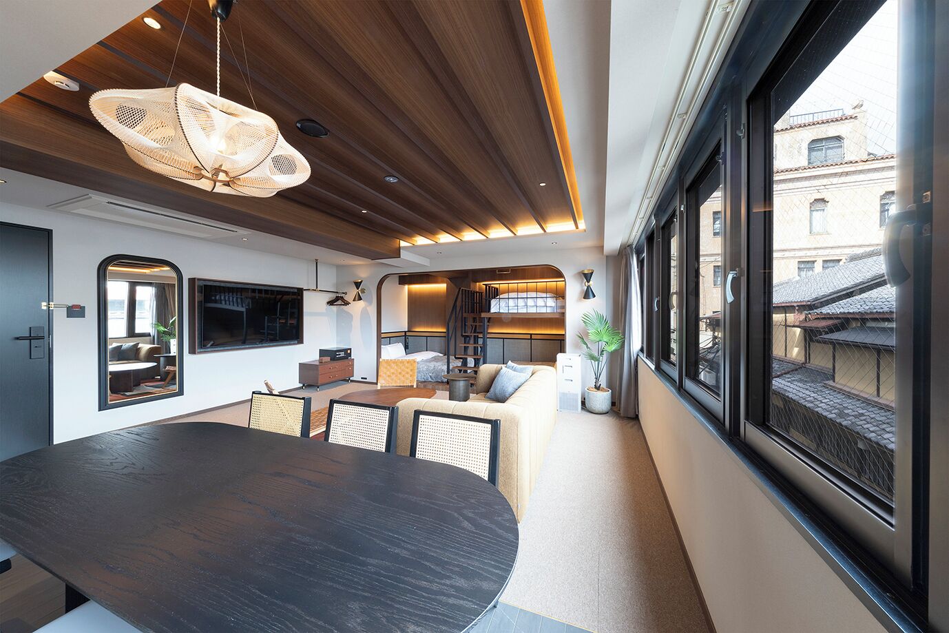 Un intérieur moderne comprenant un coin repas, un canapé, un lit et une grande fenêtre.