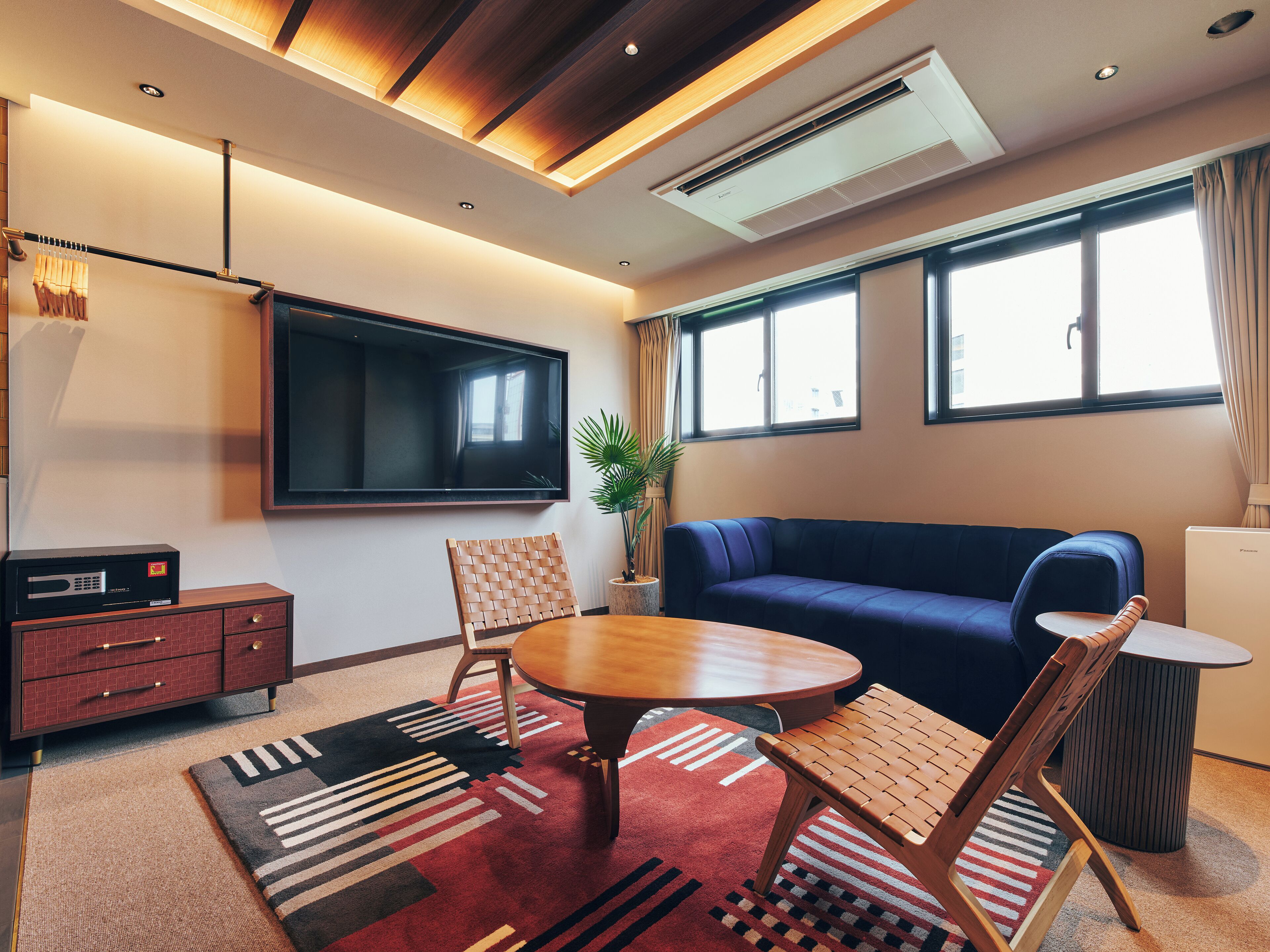 A modern living room with a blue sofa, a wooden coffee table, and a TV mounted on the wall.