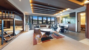 A modern hotel room with a loft-style bed, a dining area with a round table, and a kitchen with a view. - STITCH HOTEL KYOTO (Kyoto)