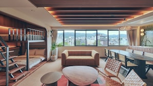 A modern living room with a bunk bed, a sofa, a dining table, and a view of the city. - STITCH HOTEL KYOTO (Kyoto)