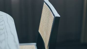 A chair with a woven backrest and a metal frame, positioned in a room with a dark background.