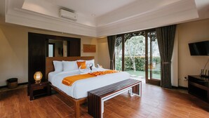 A spacious bedroom with a large bed, a wooden bench, a nightstand, and a TV. - Villa Anggrek Jimbaran (Jimbaran)