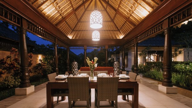An outdoor dining area with a thatched roof, wooden pillars, and a table set for four. - Villa Anggrek Jimbaran (Jimbaran)