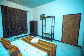 A hotel room with a bed, a wardrobe, a shelf, and a door. - Queen's Villa (Habaraduwa)