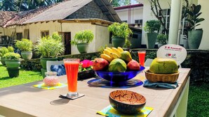 Een buitentafel gedekt, met een fruitschaal, een glas sap en een schaal eten.