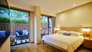Un dormitorio con una cama grande, suelo de madera, pared de ladrillo y vistas a un jardín por una puerta de cristal.