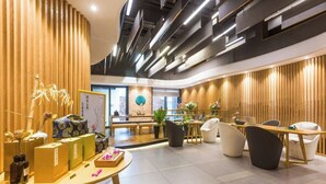 Un interior moderno con paneles de madera, mostrador de recepción, zona de estar y un ventanal.