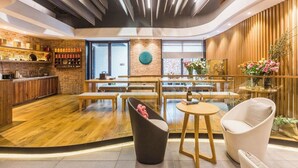 Un interior moderno con suelo de madera, una pared de ladrillo decorativa y una zona de estar con mesas y sillas.