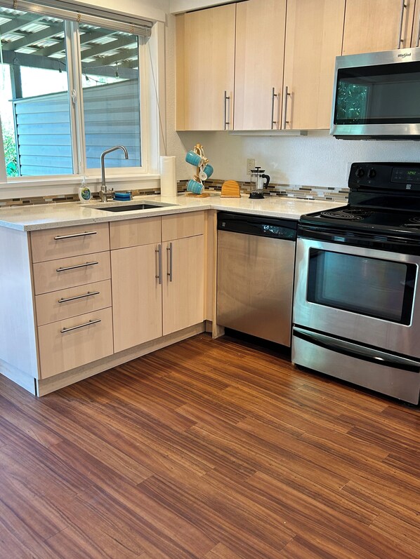 A modern kitchen with wooden cabinets, a dishwasher, a stove, and a microwave. - Charming 2-bedroom condo with WiFi in Bellingham (Bellingham)
