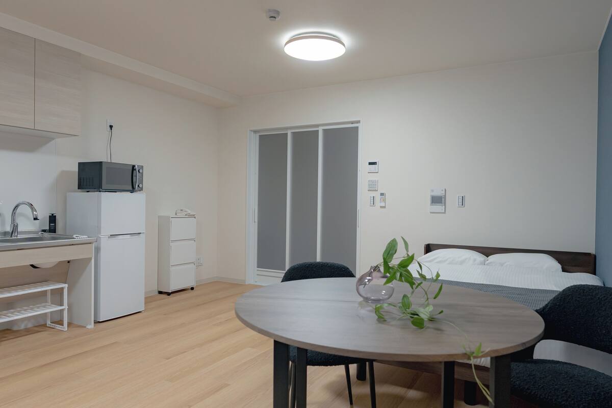 Une pièce compacte comprenant un coin cuisine, une table à manger, un lit et un placard avec porte coulissante.