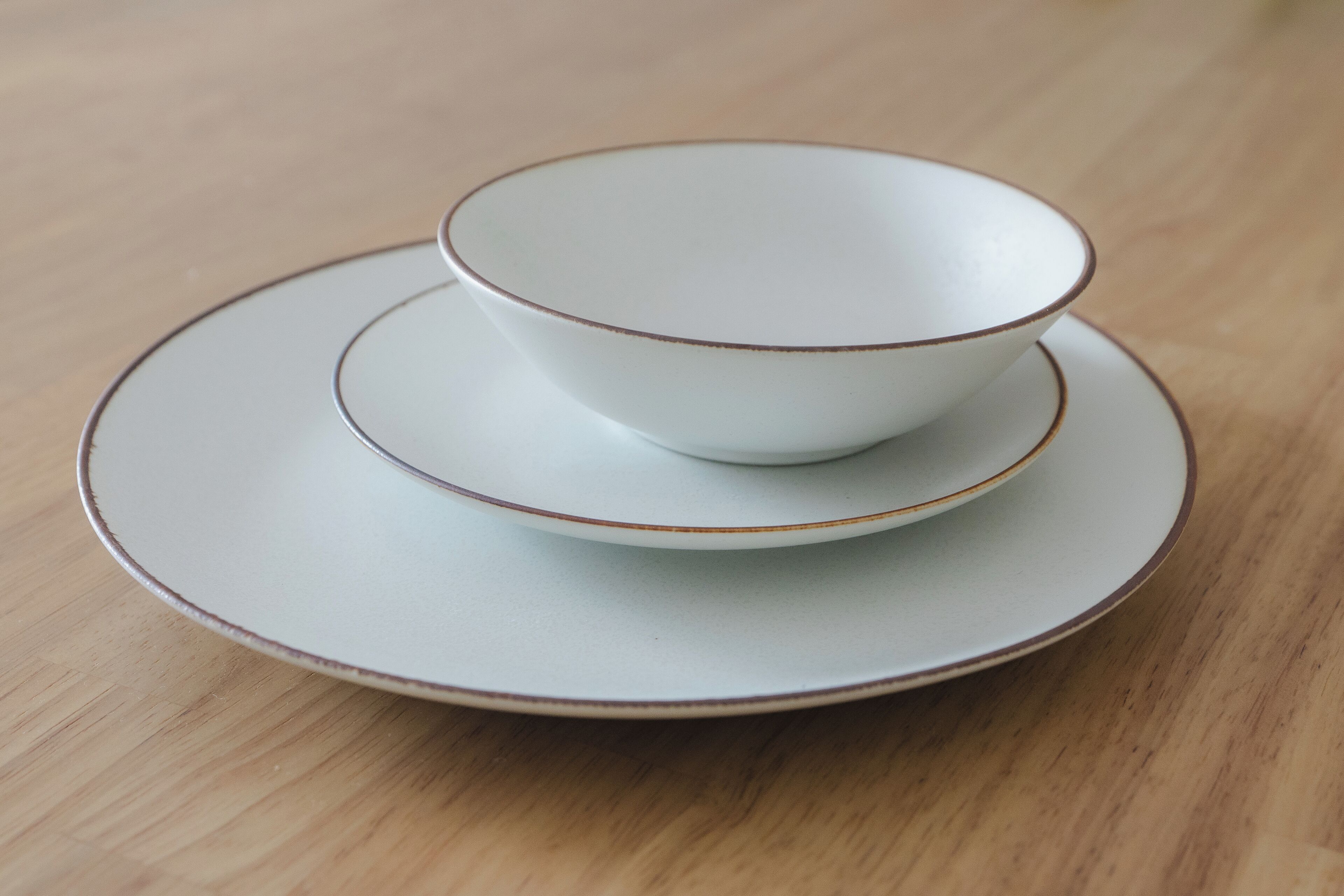 A white ceramic cup and saucer set on a wooden table.