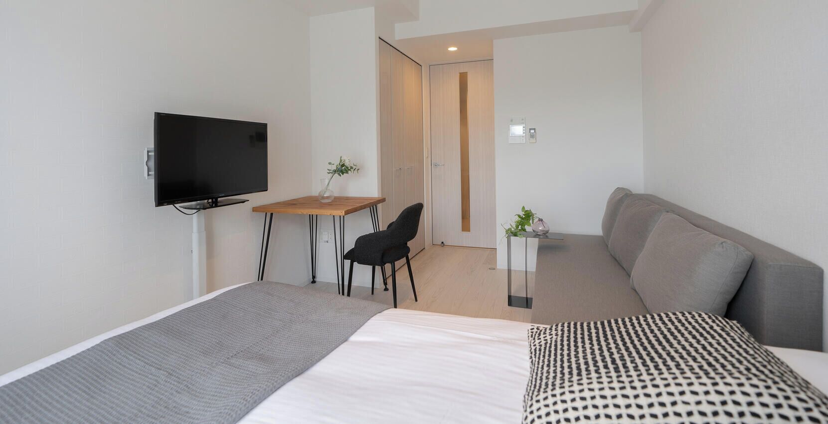 Een moderne hotelkamer met een bed, een televisie, een bureau en een bank.
