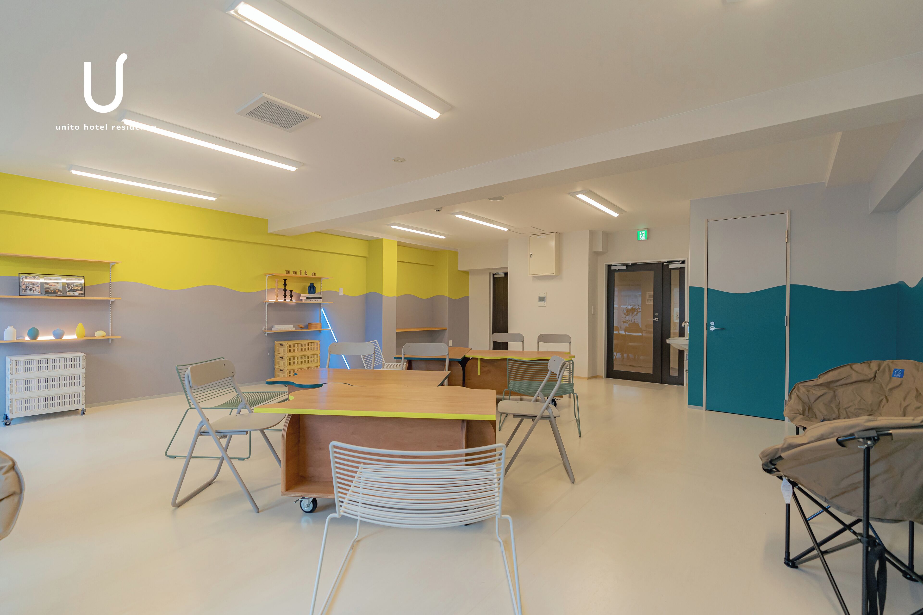 A modern hotel lobby with a central reception desk, seating area, and a children's play area.