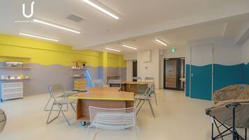 A modern hotel lobby with a central reception desk, seating area, and a children's play area.