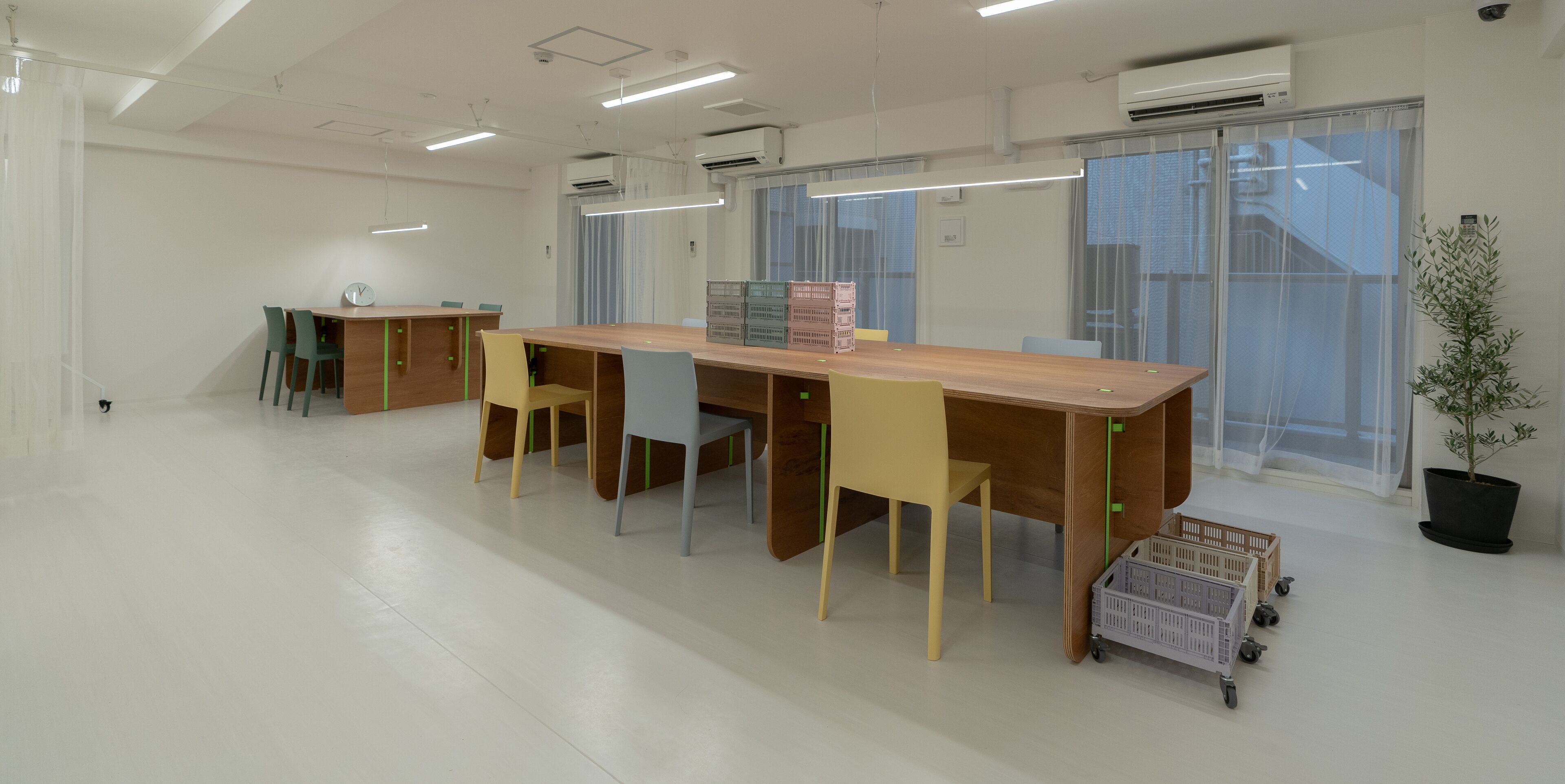 A spacious, well-lit meeting room with a long wooden table, several chairs, and a potted plant.