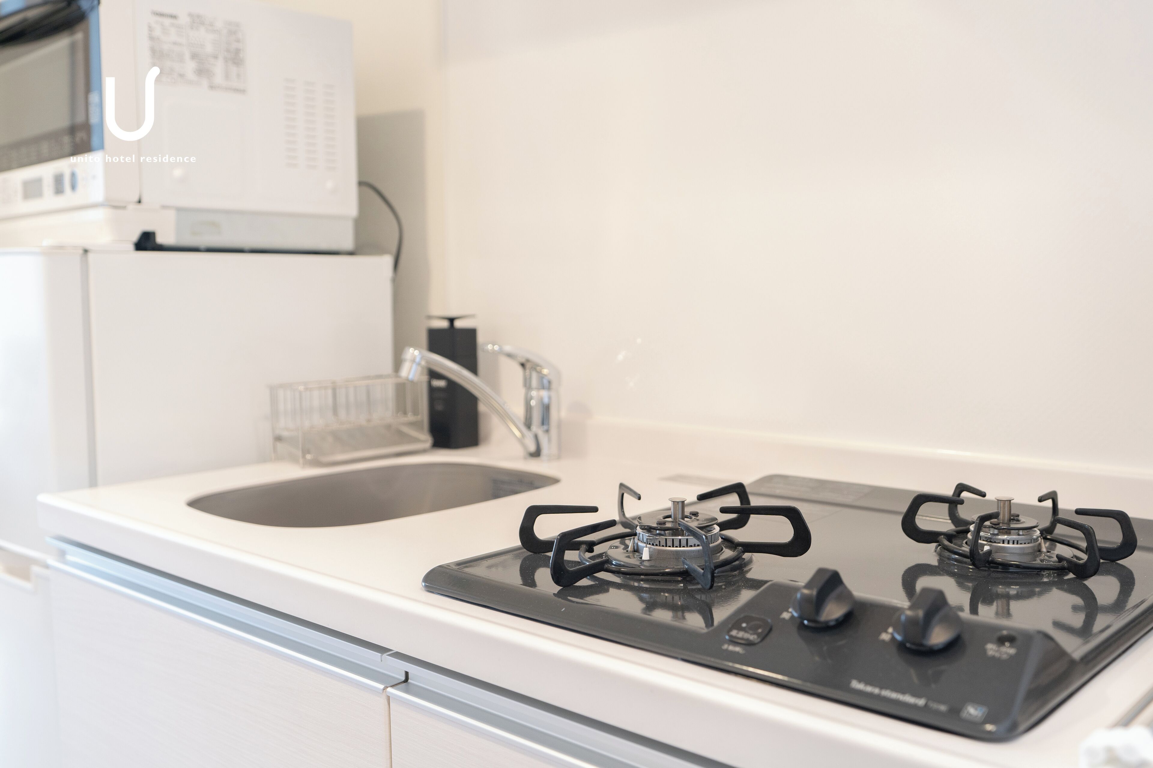 A modern kitchen with a gas stove, a sink, and a microwave.