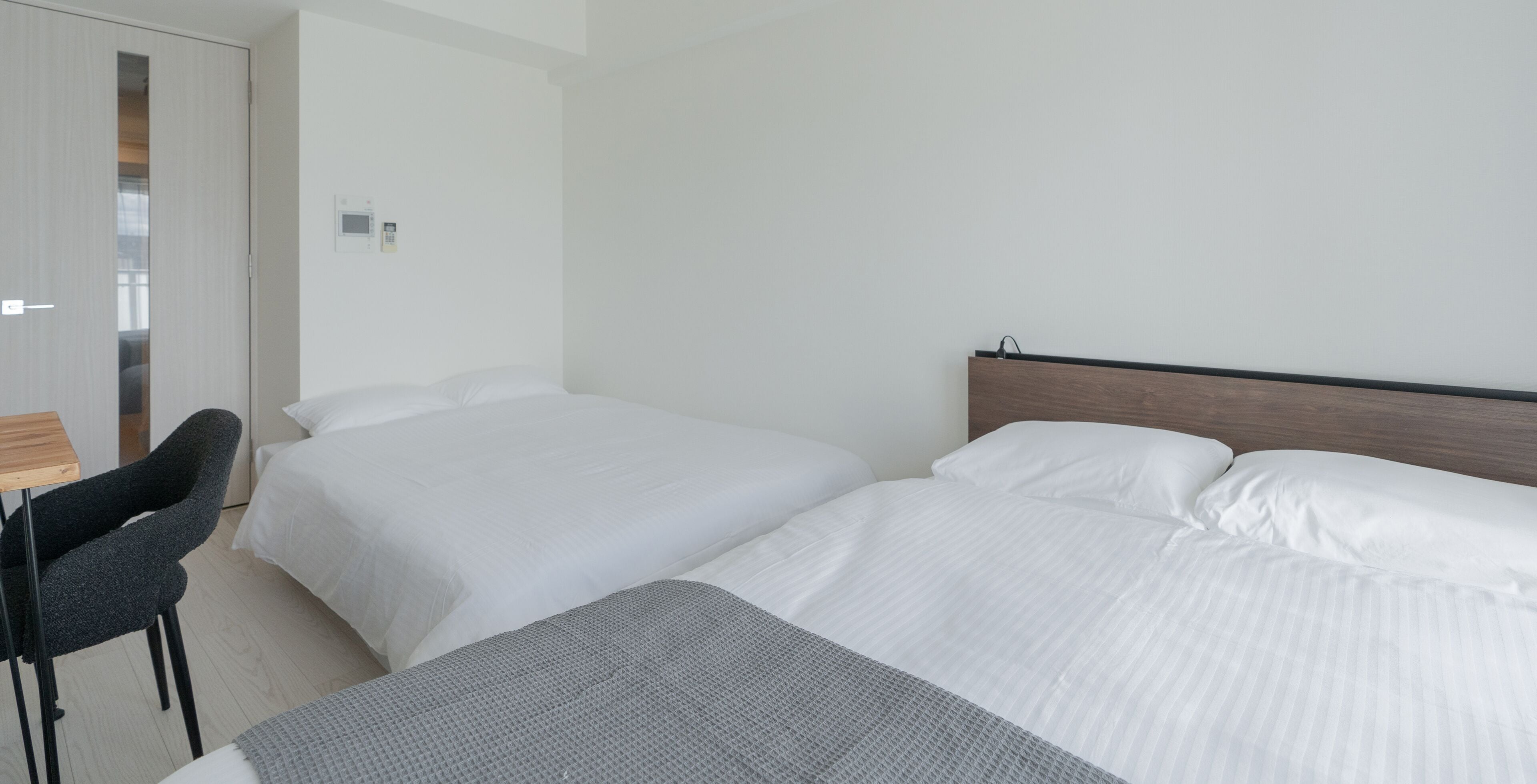 Ein Hotelzimmer mit zwei Betten, einem Schreibtisch und einem Sessel.