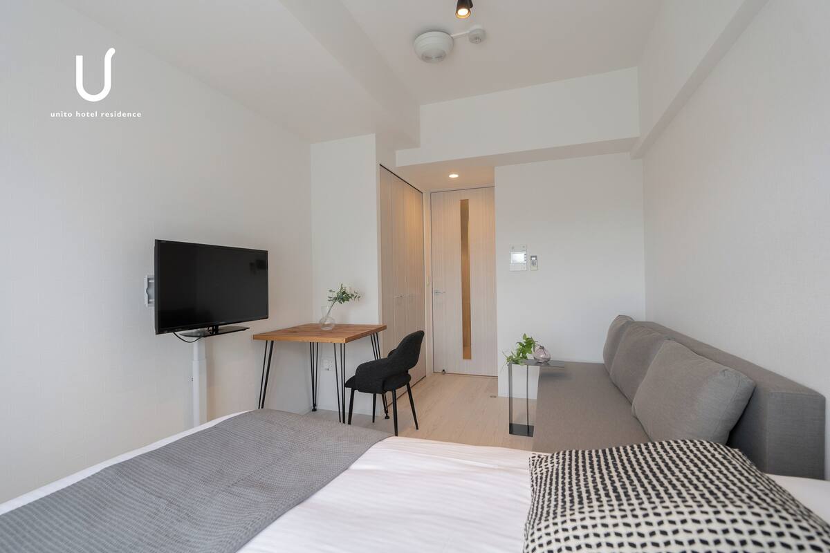 Une chambre d’hôtel moderne équipée d’un lit, d’un bureau, d’une chaise, d’un canapé et d’une télévision.