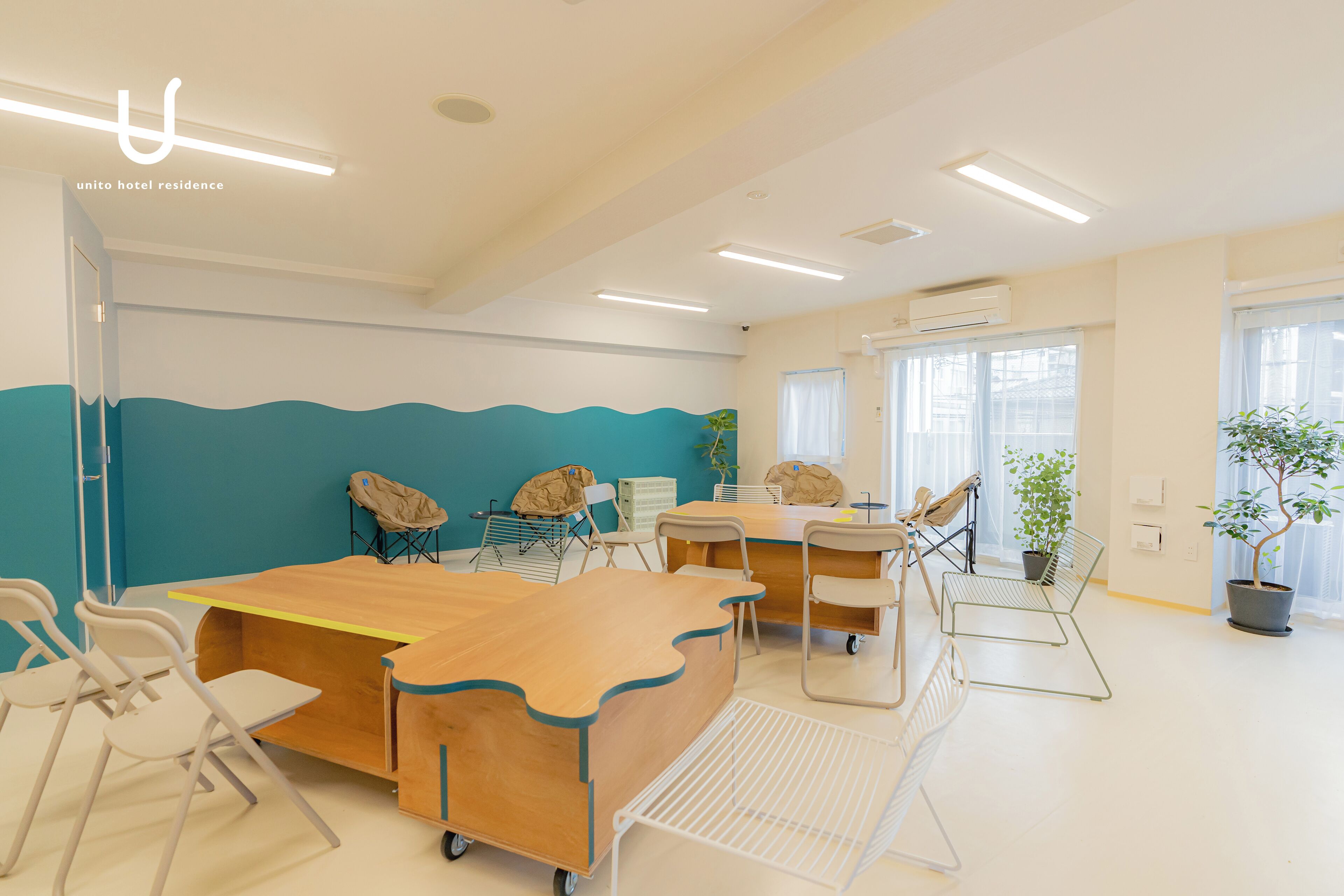Una habitación luminosa y moderna con una pared de acento color turquesa, una mesa de madera y varias sillas.