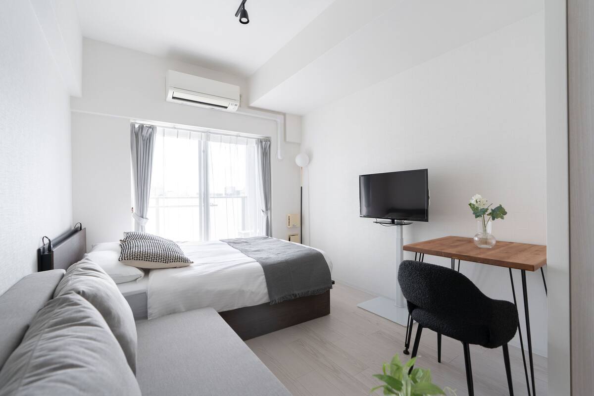 Une chambre d’hôtel moderne équipée d’un lit, d’un canapé, d’une télévision et d’une petite table.