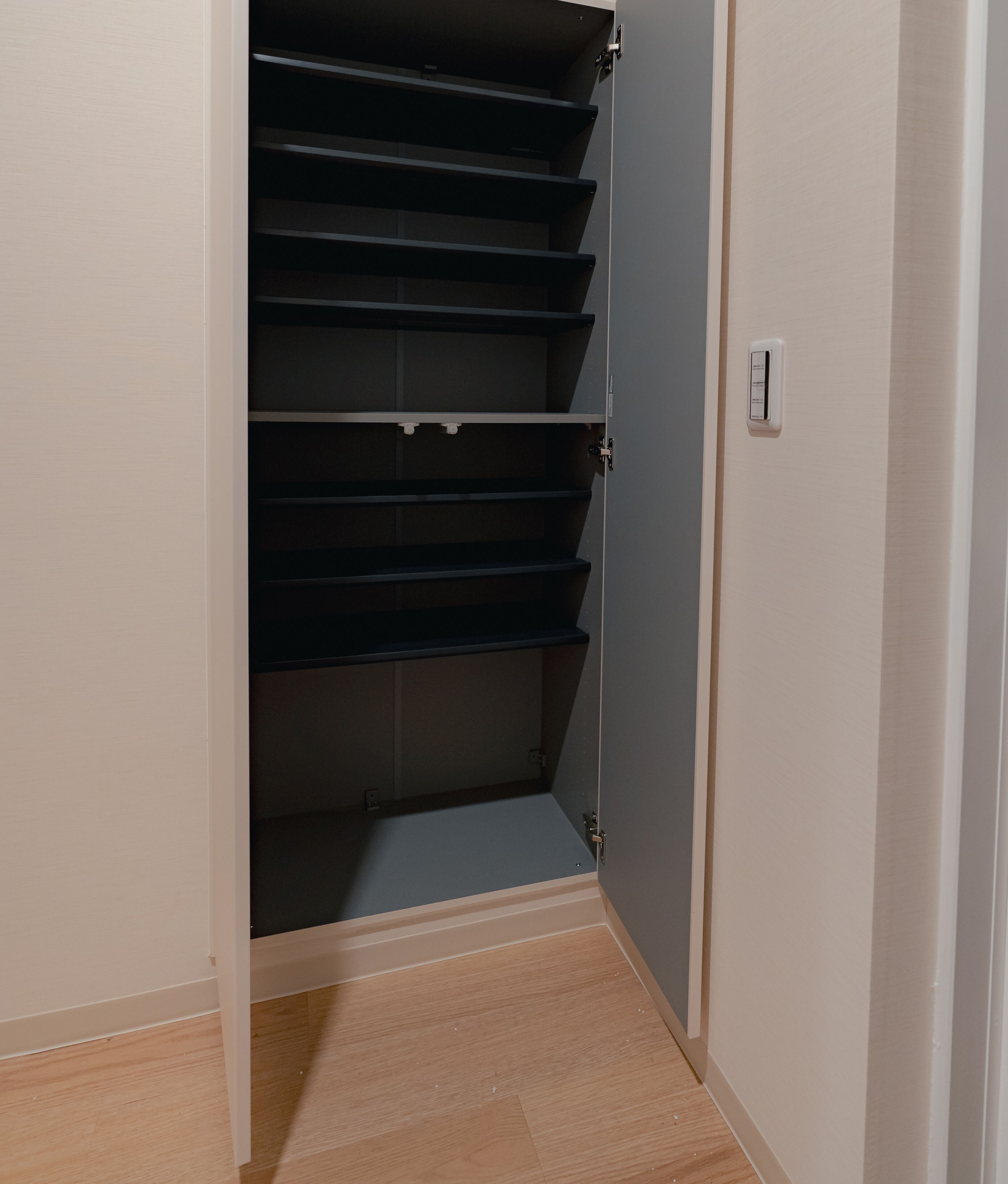 A closed wardrobe with multiple shelves and a door handle.
