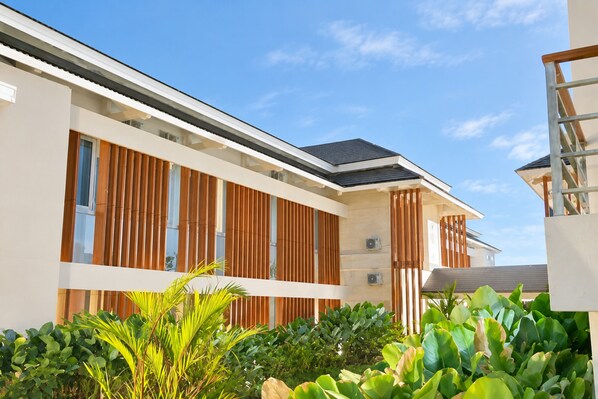 A modern building with a flat roof, large windows, and a well-maintained garden with various plants. - Horison Resort Antawirya Jepara (Tahunan)