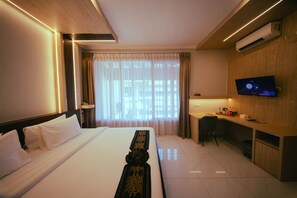 Een hotelkamer met een bed, een bureau, een televisie en een airconditioning.