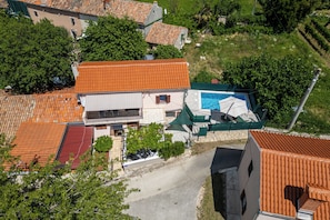 Eine Vogelperspektive auf eine Wohngegend mit Terrakotta-Dachziegeln, einem Swimmingpool und umgebender Bepflanzung.