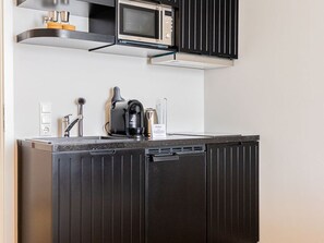 A kitchen with a microwave, coffee maker, and kettle on the counter.