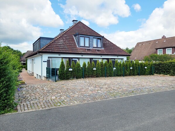Ein modernes Haus mit Satteldach, befestigter Auffahrt und gepflegtem Heckenstreifen.