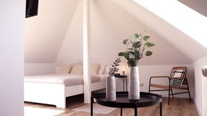 Ein Schlafzimmer mit einem Bett, einem Sessel, einem kleinen Tisch und zwei Vasen mit Pflanzen.