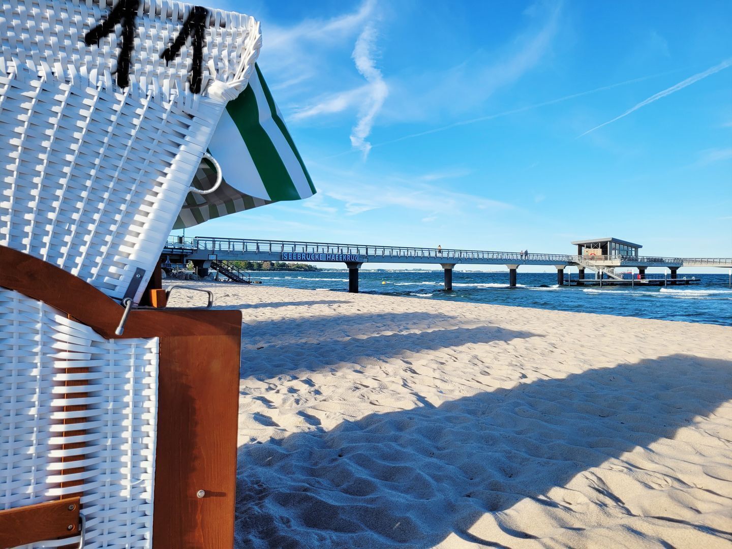 Ein Strand mit einer Holzterrasse und einem Steg, der ins Wasser führt.