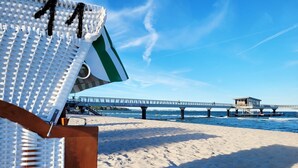 Ein Strand mit einer Holzterrasse und einem Steg, der ins Wasser führt.