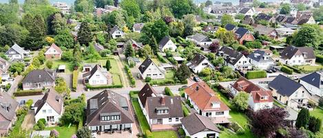 A residential area with houses, green lawns, and a view of the sea.