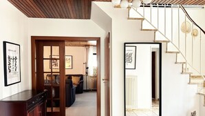 A modern interior with a wooden staircase, a mirrored wall, and a dark-toned cabinet.