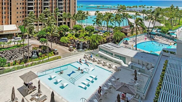 A resort with a pool, palm trees, and a view of the beach. - 2 Queen Beds Beachfront Home (Car Available) (Honolulu)