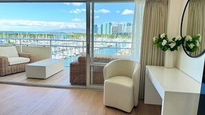 A modern living room with a view of a marina and city skyline. - 2 Queen Beds Beachfront Home (Car Available) (Honolulu)