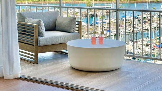 Un balcone con vista sull'oceano, un divano e un tavolino rotondo.