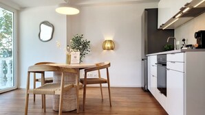 Een moderne keuken met een eethoek, houten vloeren en een groot raam.