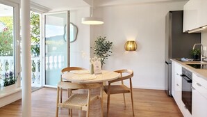 Een moderne keuken met witte kasten, een ronde eettafel met stoelen, een hanglamp en een wandlamp.