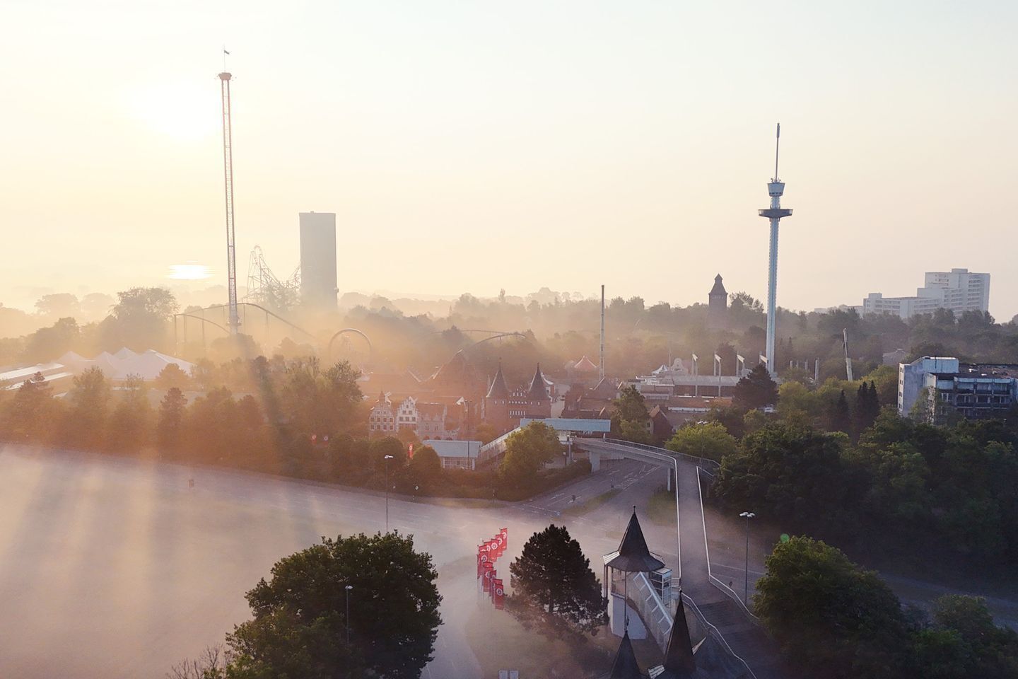 Eine Stadtansicht mit einem markanten Turm, einer Brücke und einer Mischung aus moderner und traditioneller Architektur.