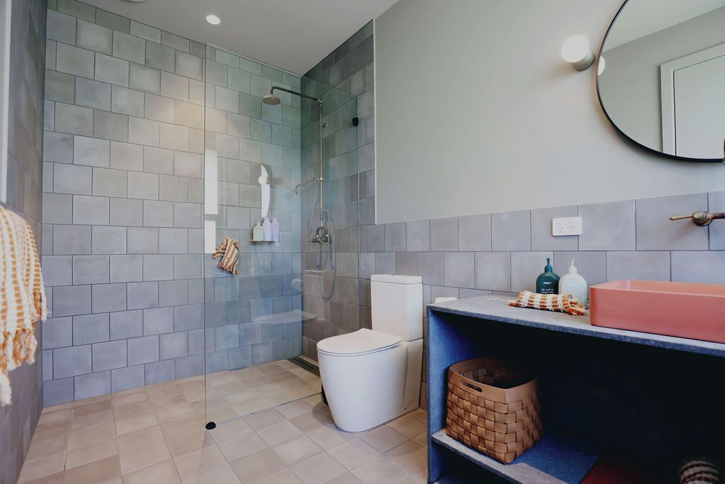 Un baño moderno con ducha envuelta en vidrio, inodoro blanco y tocador con espejo.