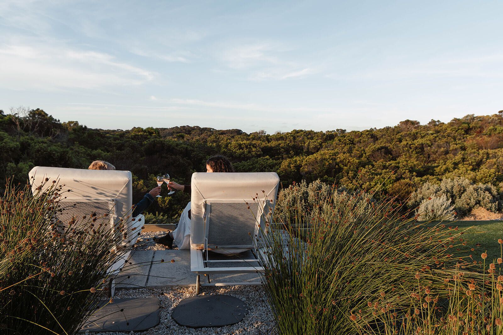 Two lounge chairs facing a natural landscape with a view of a forested hill.