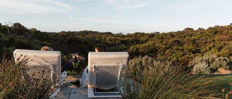 Two lounge chairs facing a natural landscape with a view of a forested hill.